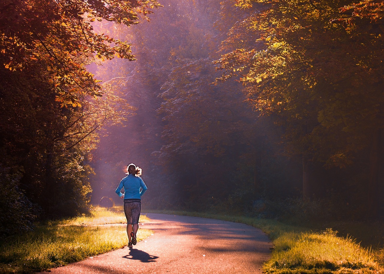 Vrouw in een blauw jack aan het hardlopen in een bos