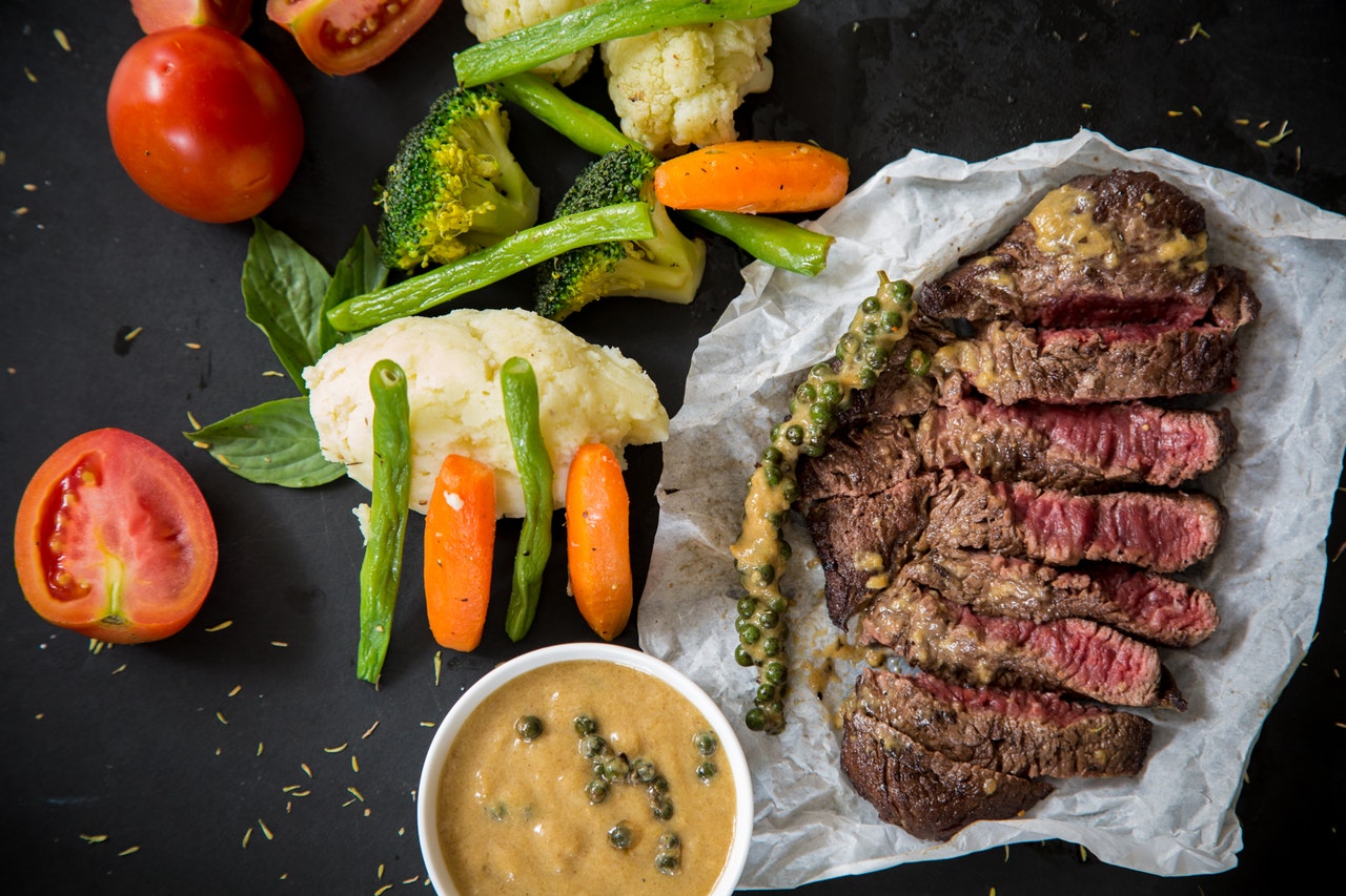 Een tafel met daarop veel voeding met ijzer, zoals steak en groenten