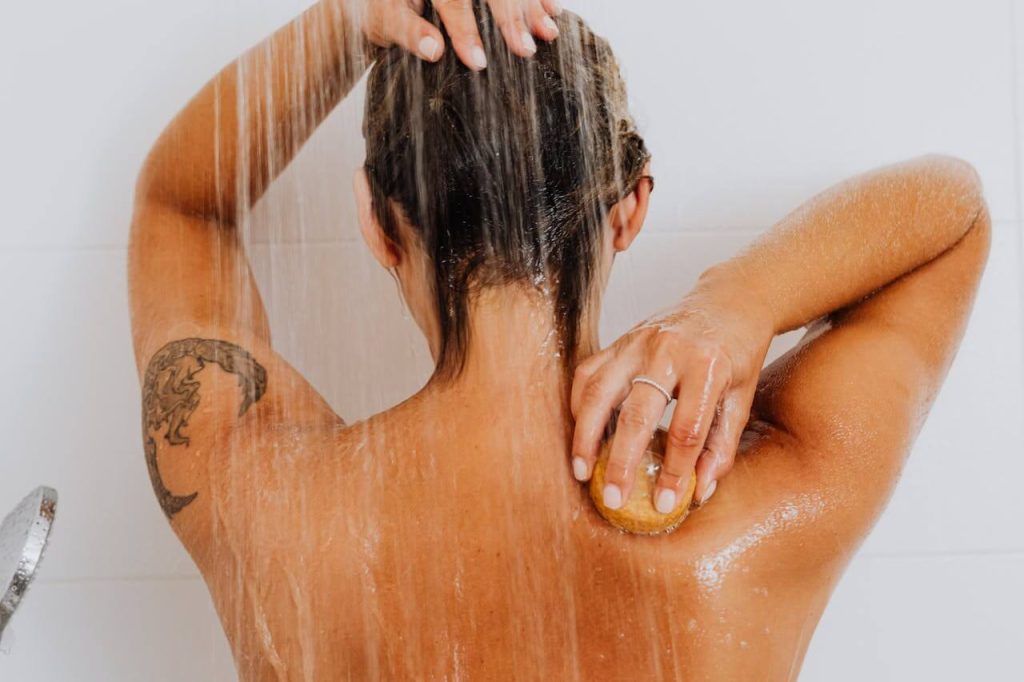 Achteraanzicht van een vrouw die aan het douchen is met koud water