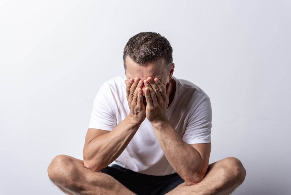 Man in wit shirt kapt met stress en plaatst handen over zijn hoofd