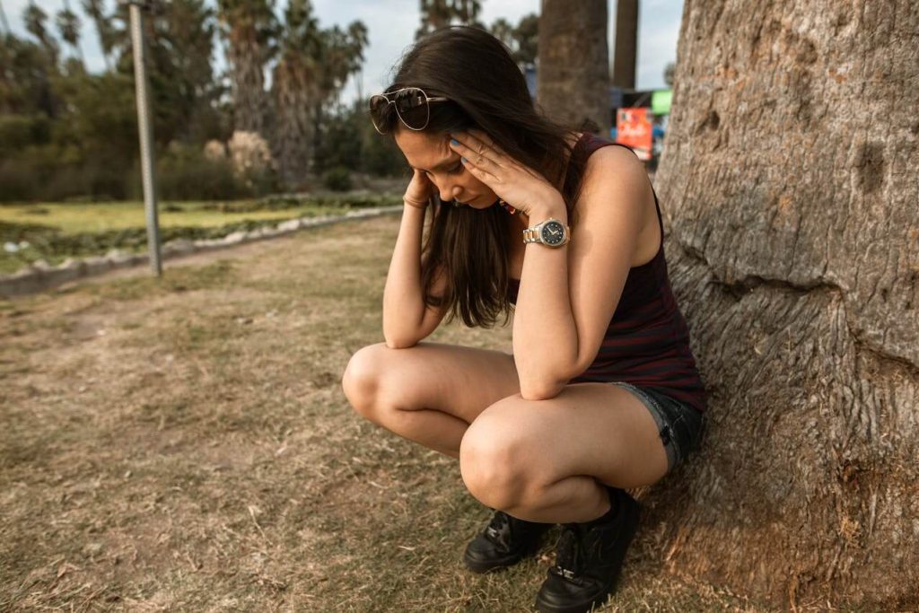 Vrouw zit tegen een boom aan vanwege acute stress