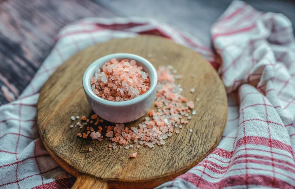 roze zout in een wit kommetje op een houten serveerblad