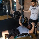 excentrisch trainen bij het bankdrukken door twee jonge mannen in een sportschool