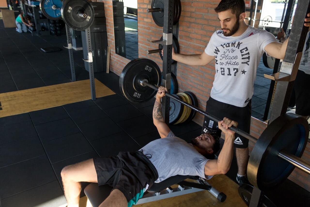 excentrisch trainen bij het bankdrukken door twee jonge mannen in een sportschool