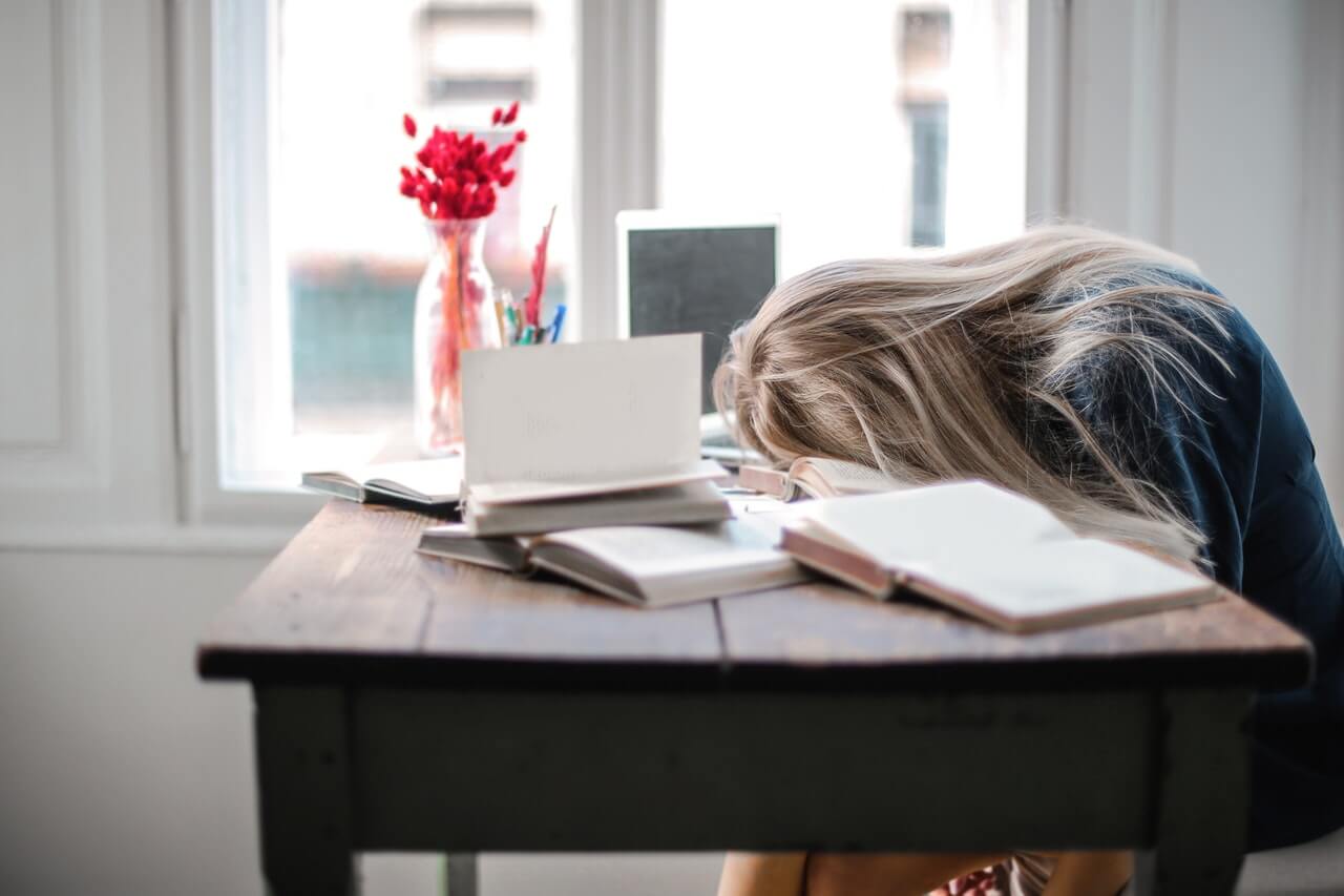 slaaptekort door een vrouw die aan het studeren is aan haar bureau
