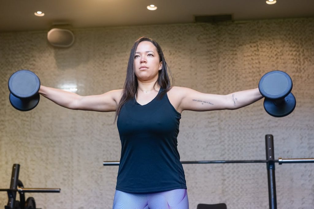 vrouw in zwart hemd die spiermassa aan het opbouwen is in de sportschool