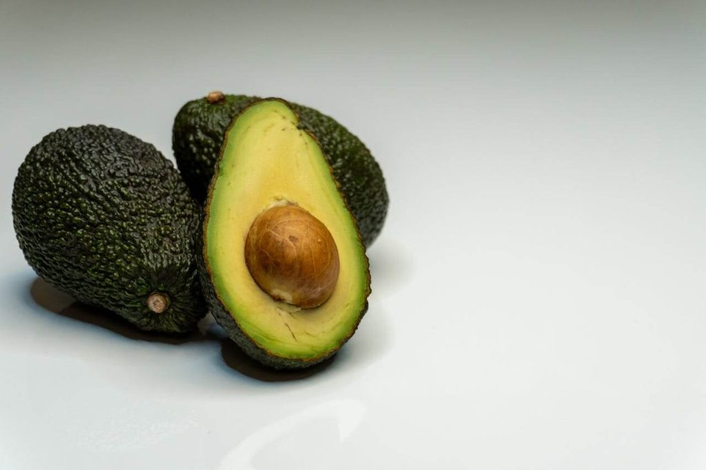 Drie avocado's waarvan er een doormidden is gesneden