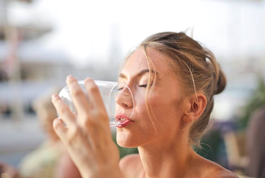 Blonde vrouw drinkt uit een glas met water