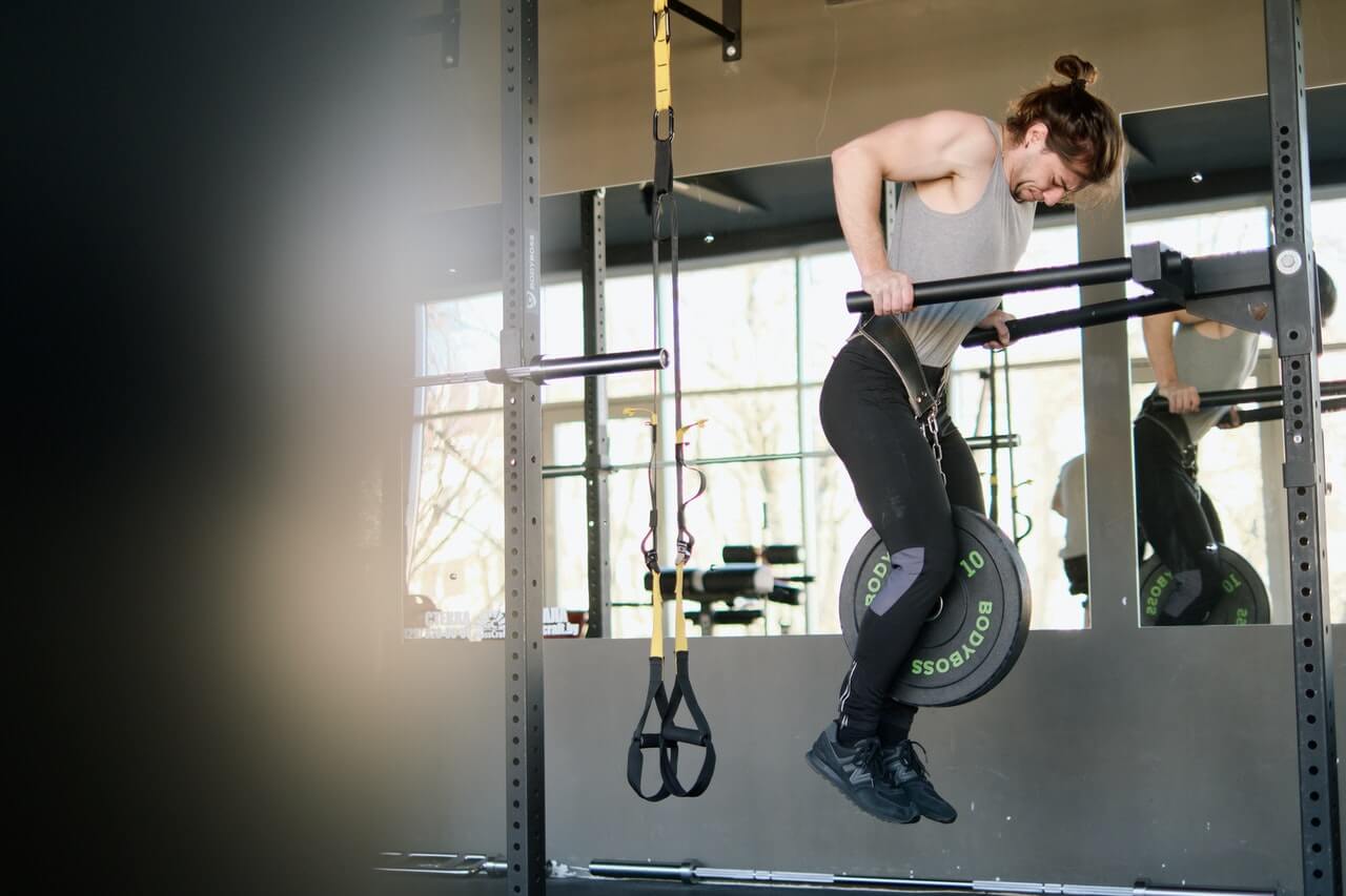 triceps dips door een man in grijs hemd in een sportschool