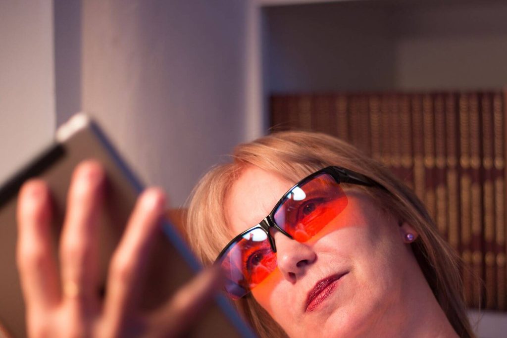 vrouw draagt blauw licht bril met oranje glazen