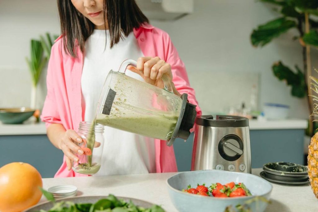 Vrouw maakt een gezonde maaltijdshake in een blender