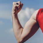 muscle memory bij een man met rood shirt die zijn biceps aanspant