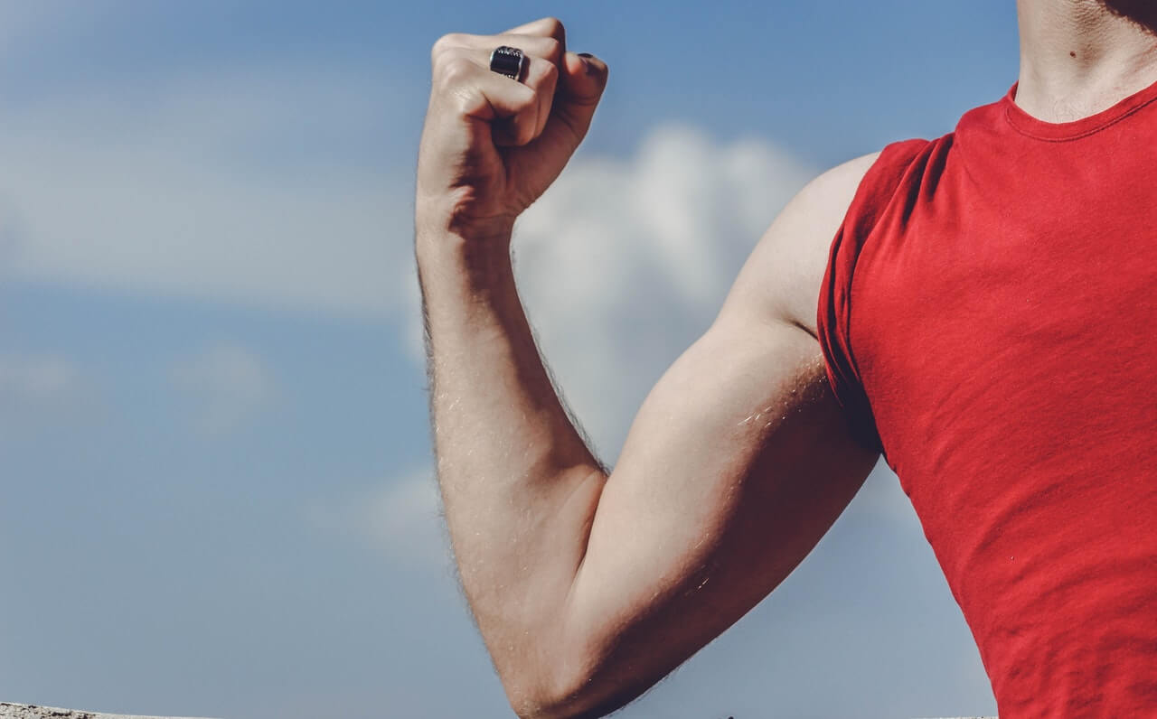 muscle memory bij een man met rood shirt die zijn biceps aanspant