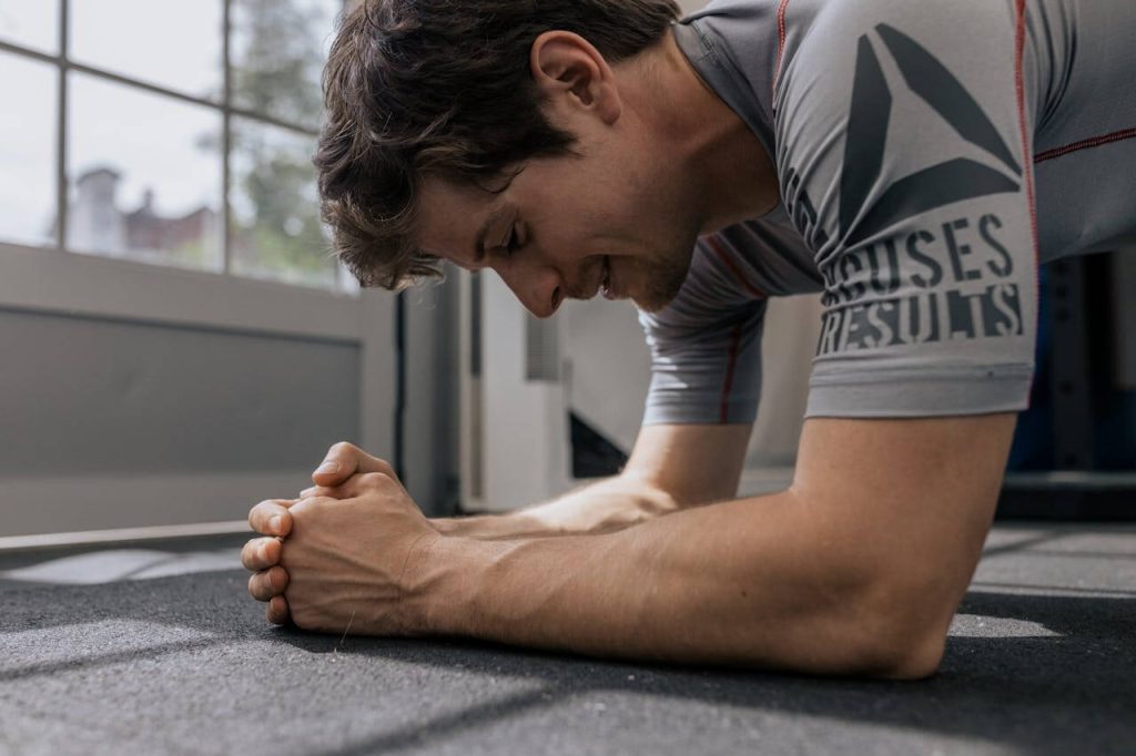 man in grijs shirt is aan het planken om zo zijn buikspieren te trainen