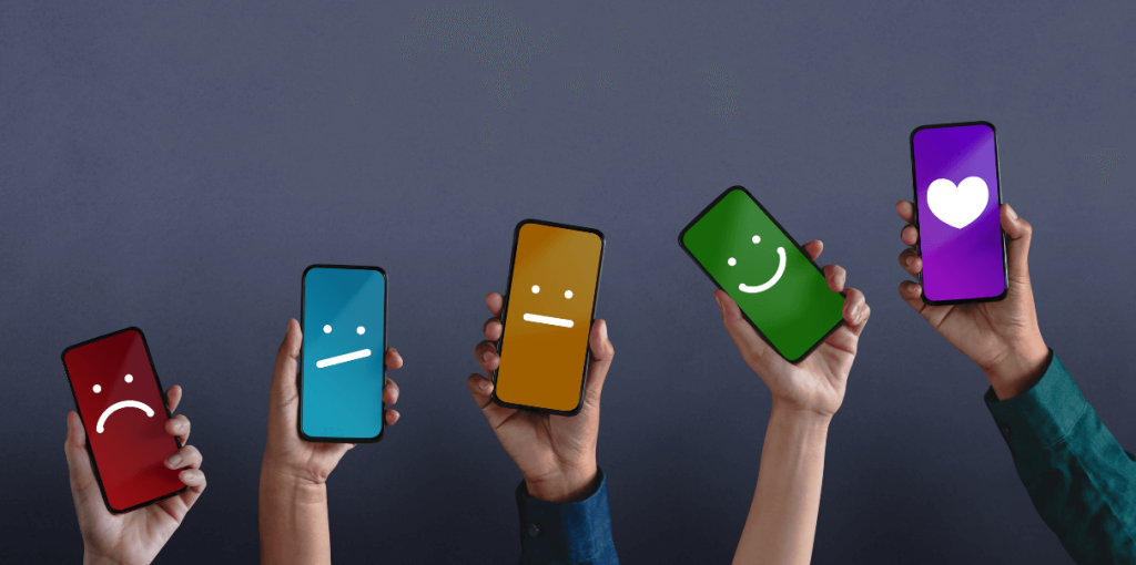 Vijf handen houden smartphones vast met verschillende emoticons: een droevige, een ontevreden, een neutrale, een glimlach en een hartje.
