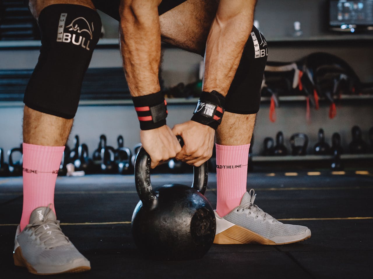 Een atleet die CrossFit schoenen draagt en een kettlebell tilt in een sportschool