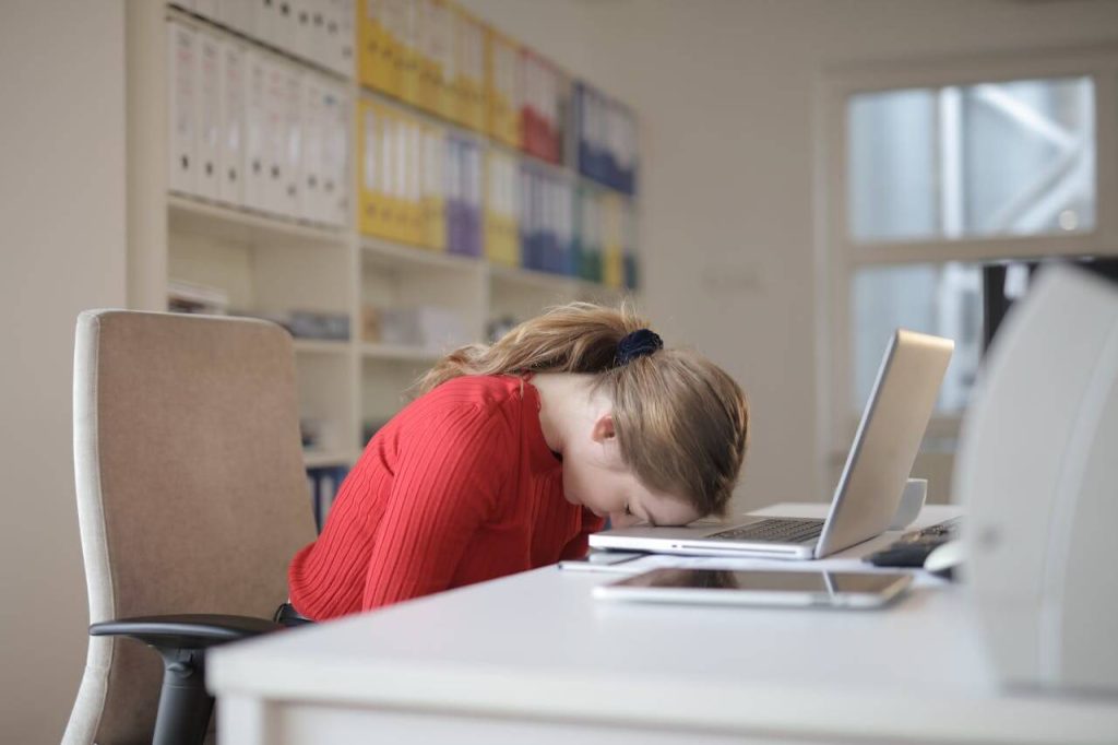 vrouw in rode trui achter een laptop heeft meer energie nodig om door te werken