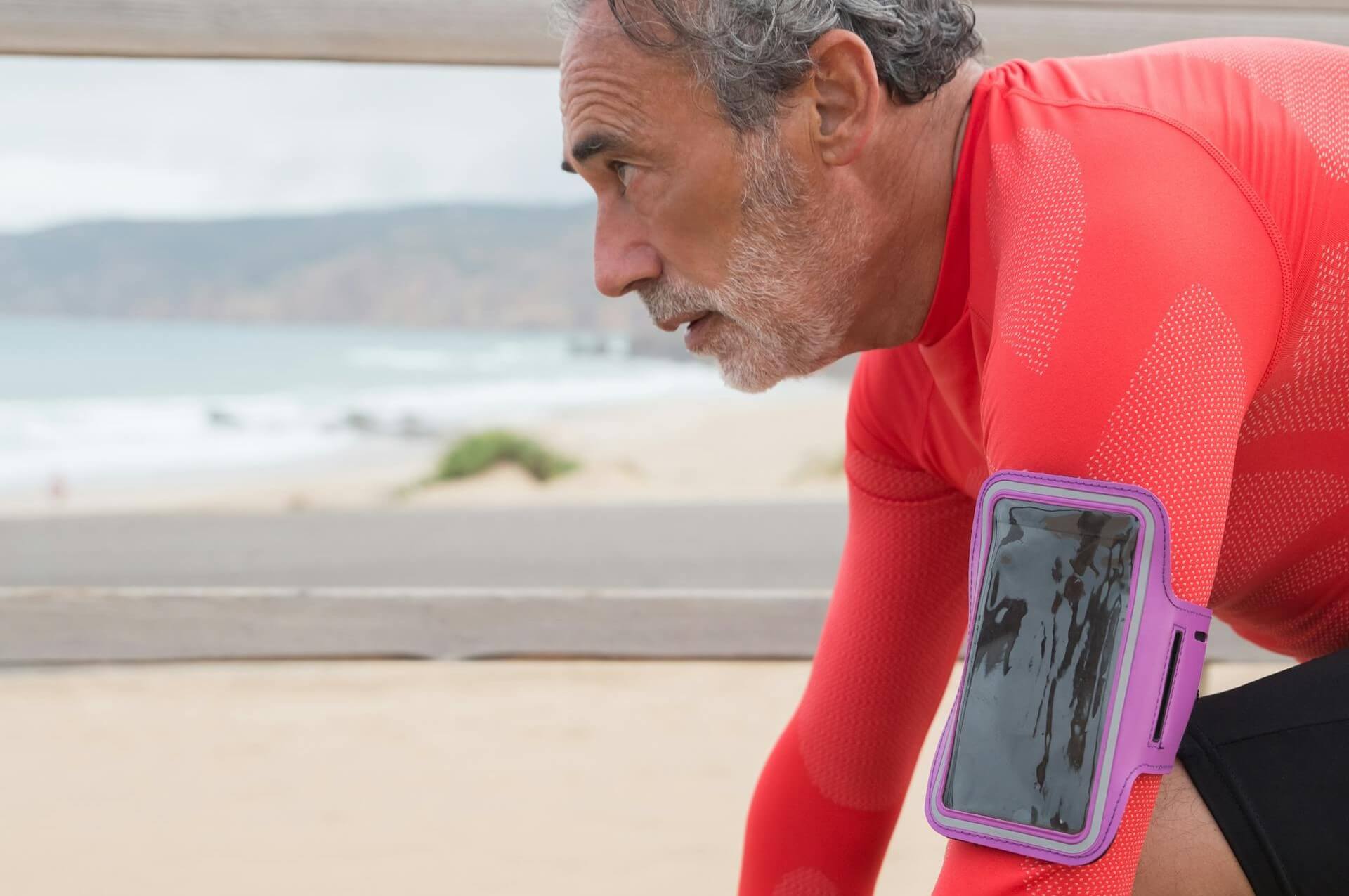 Man in rood shirt met een telefoonhouder voor hardlopen om zijn arm