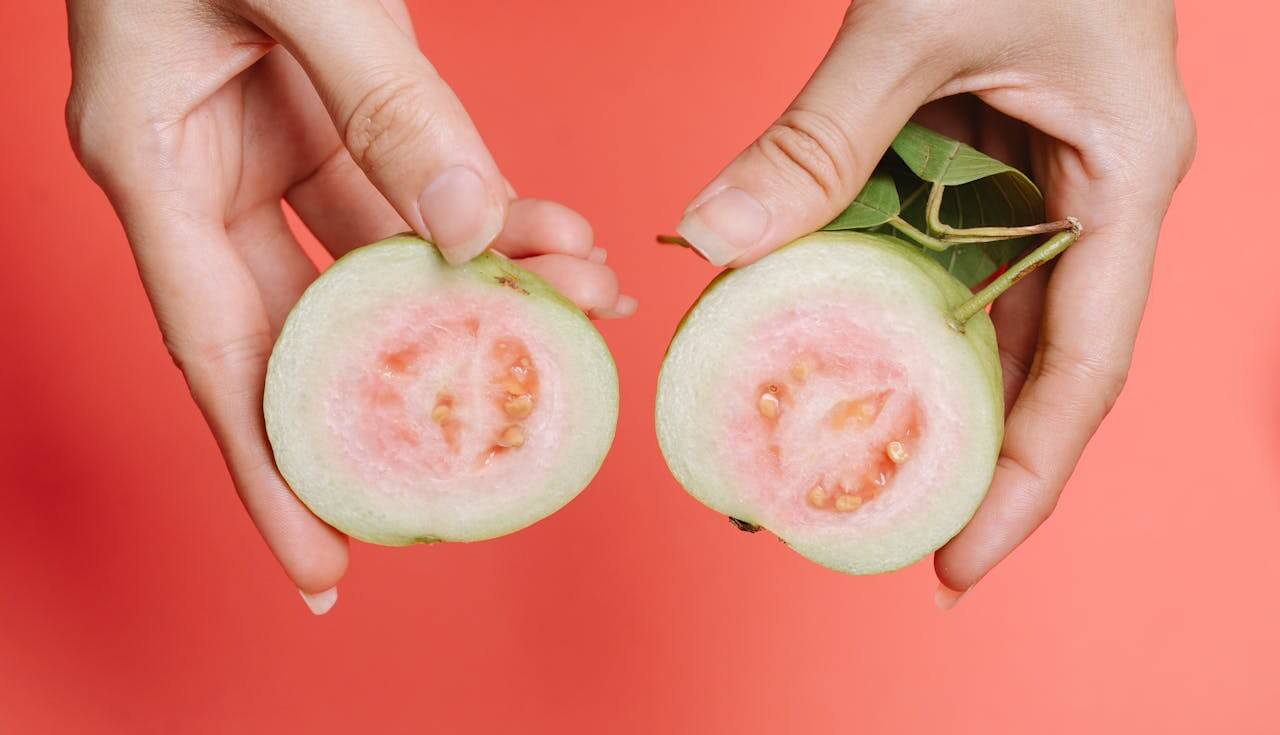 handen die een doormidden gesneden guave fruit met veel eiwitten vasthouden