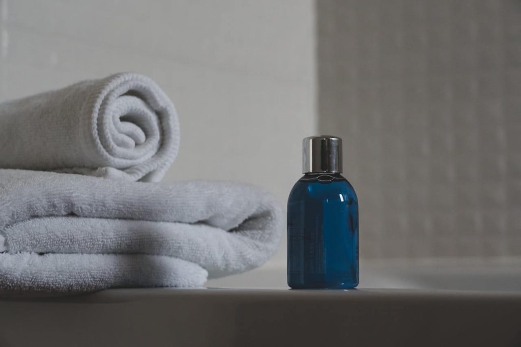 blauwe fles shampoo naast witte handdoeken
