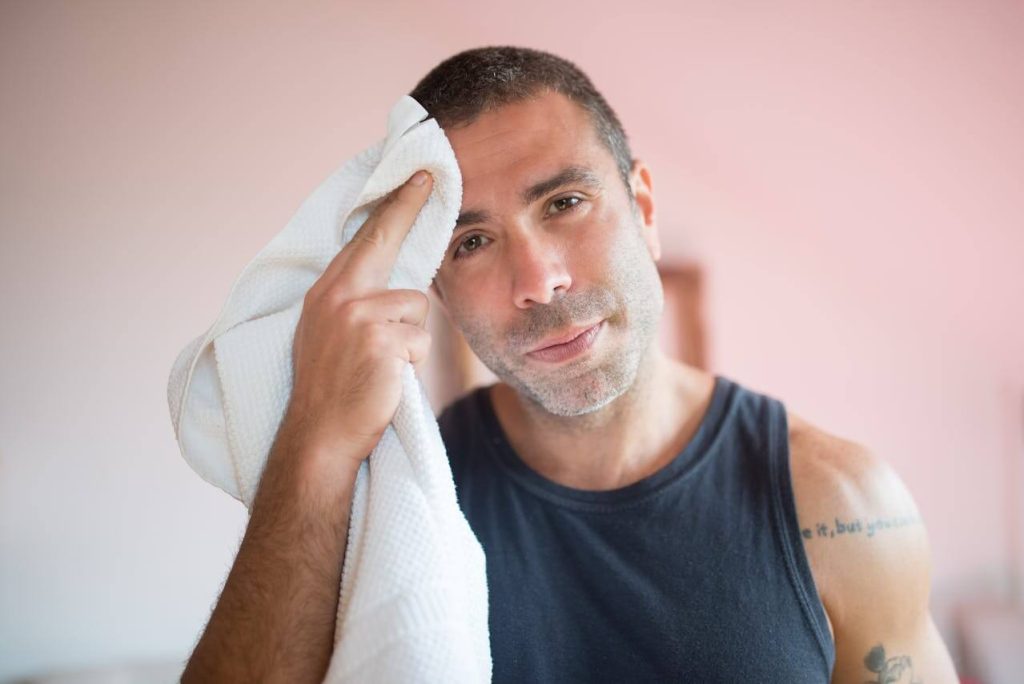 Sportieve man in tanktop gebruikte witte sporthanddoek