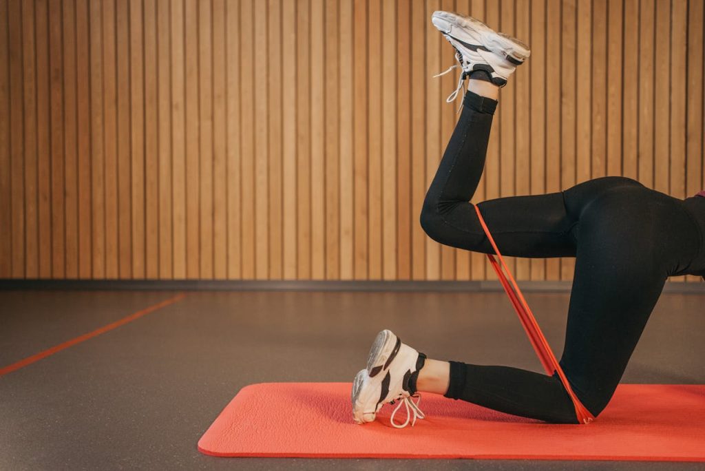 Vrouw die glute kickbacks doet met een weerstandsband op een. fitnessmat