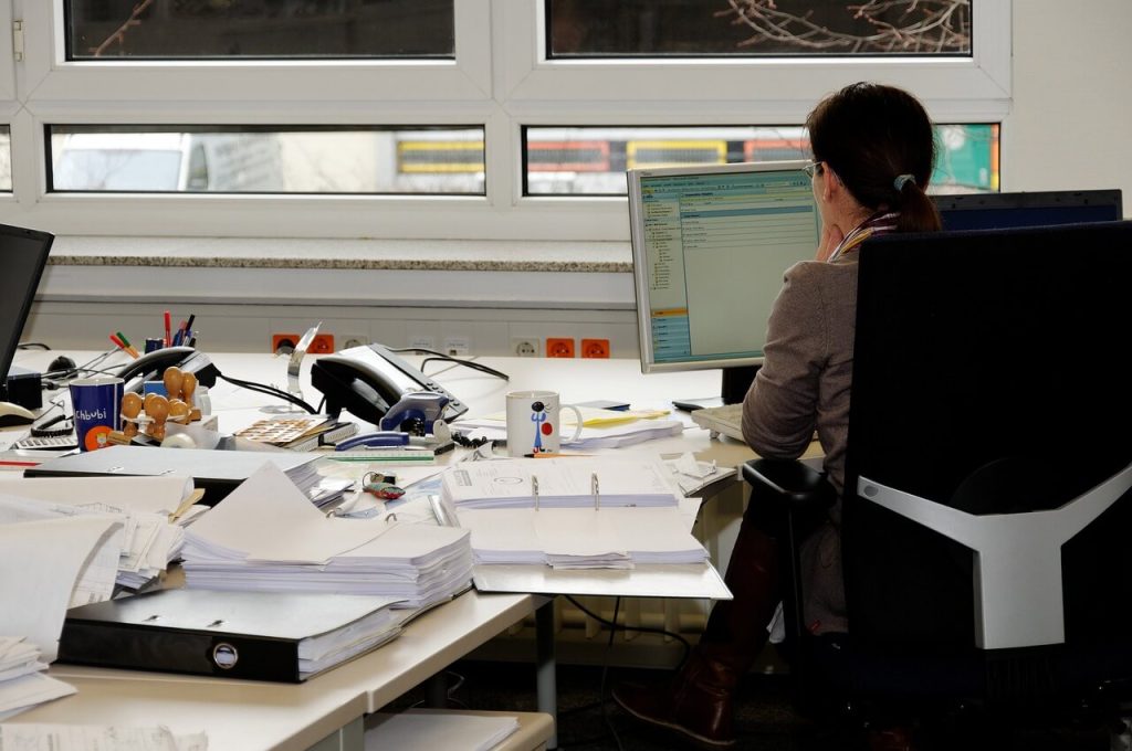 vrouw zit op kantoor en ervaart rugklachten
