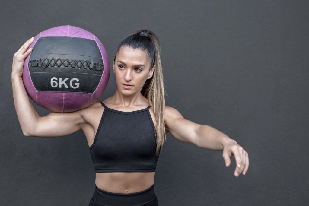 fitte vrouw met zwarte sport outfit traint met een wall ball