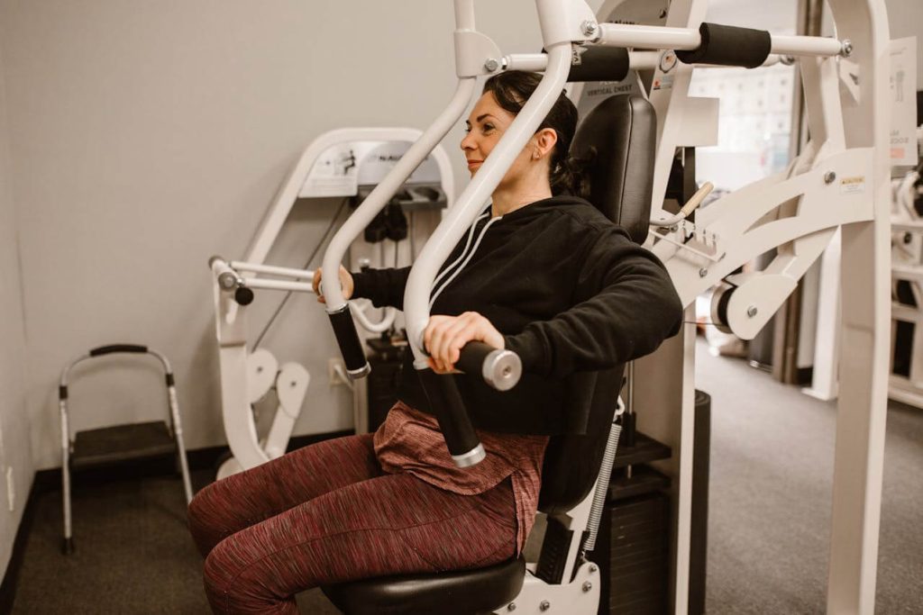 vrouw voert een chest press uit in de sportschool