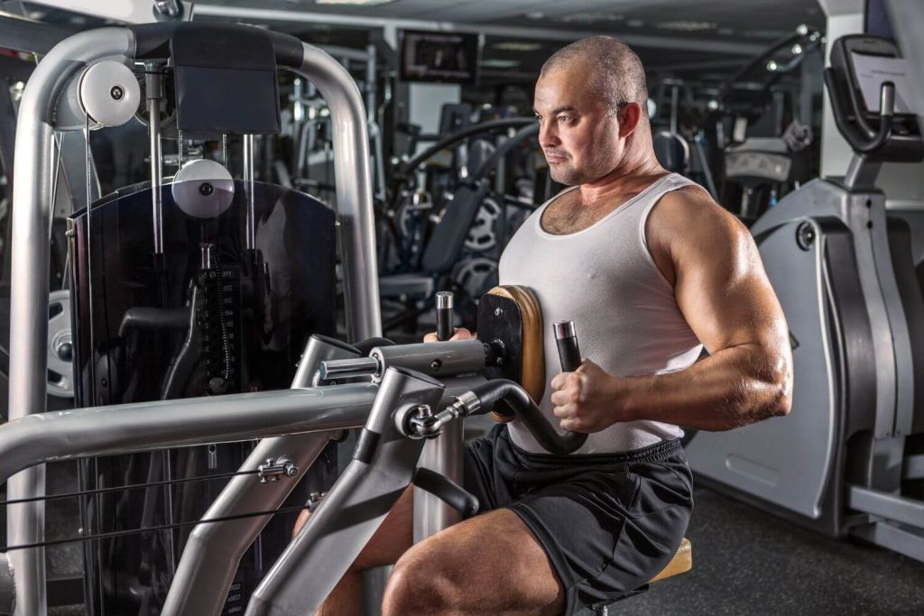 Man traint rugspieren met een machine row