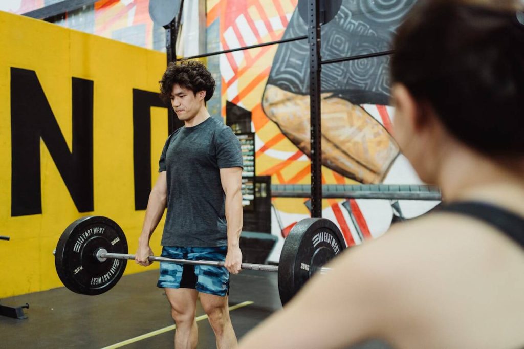 Jonge man doet een conventional deadlift terwijl zijn trainer toekijkt