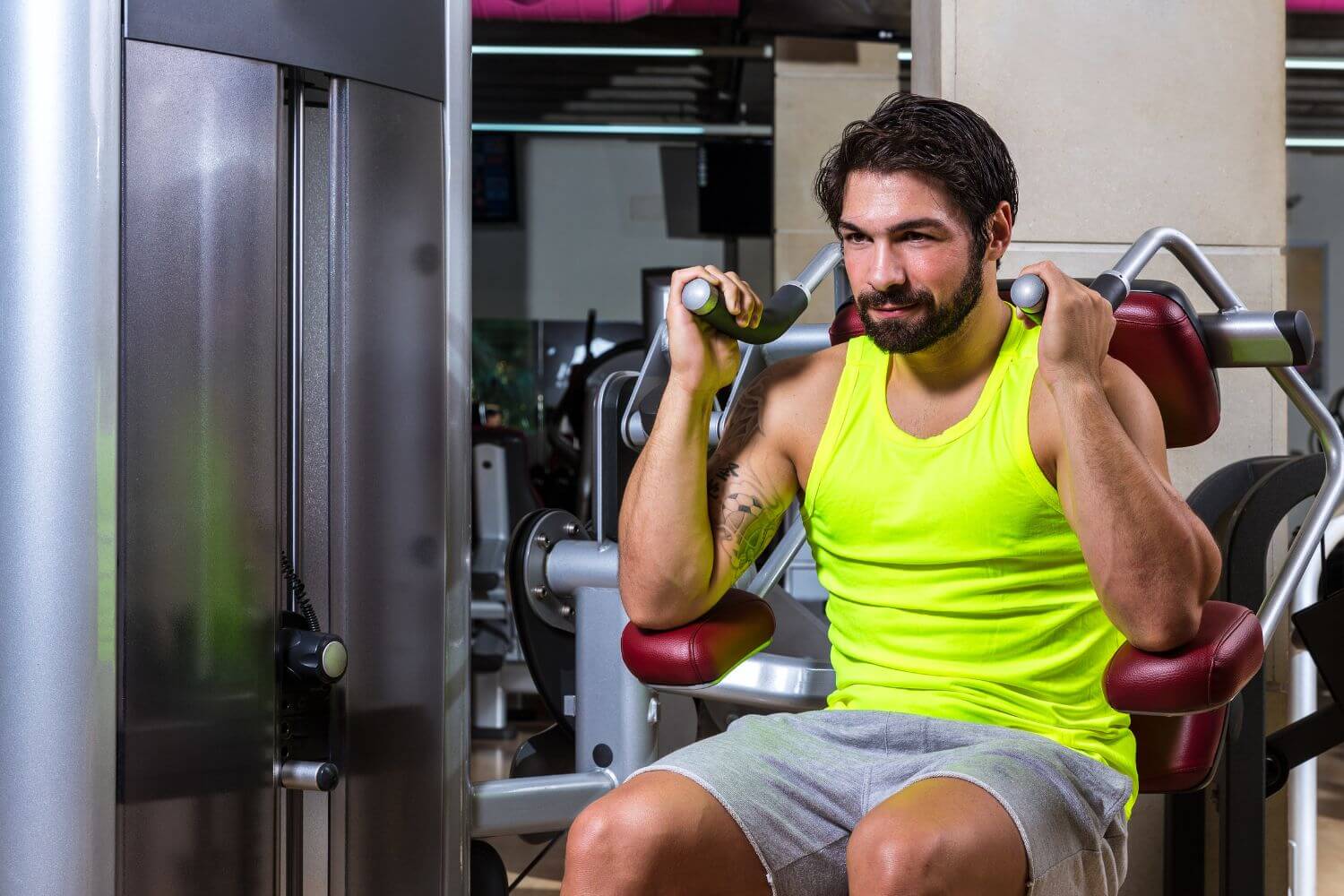 Man met geel hemd op een ab crunch machine