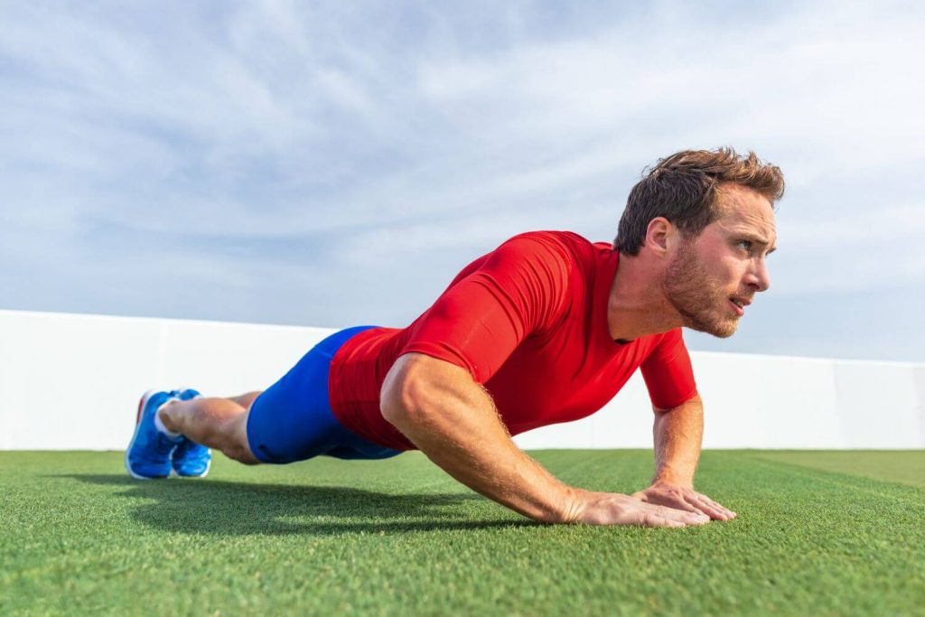 man in rood shirt traint triceps met een push-up variant