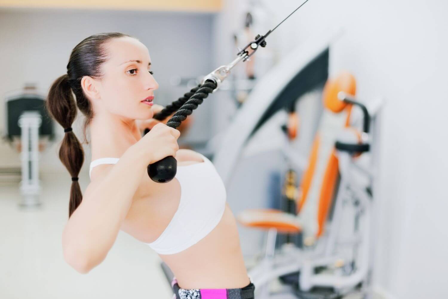 Jonge vrouw doet een face pull met kabel in de sportschool