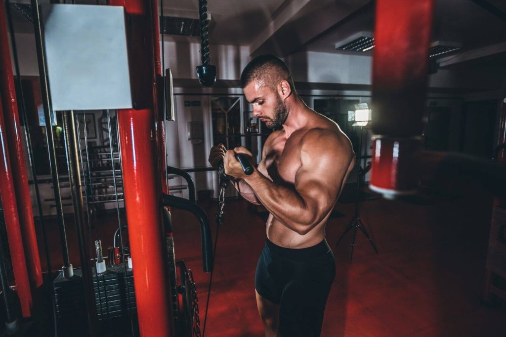 Gespierde man voert cable curls uit