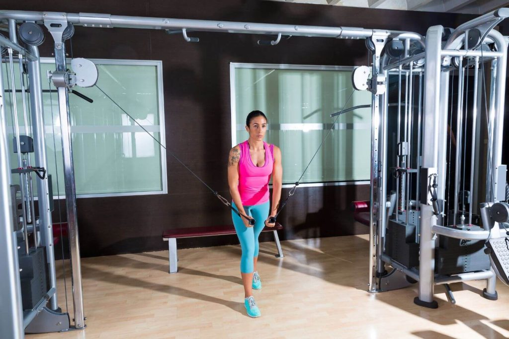 Vrouw in roze hemd doet een standing cable fly