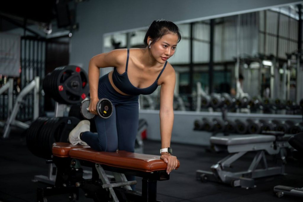 Jonge vrouw doet een dumbbell triceps kickback in een sportschool