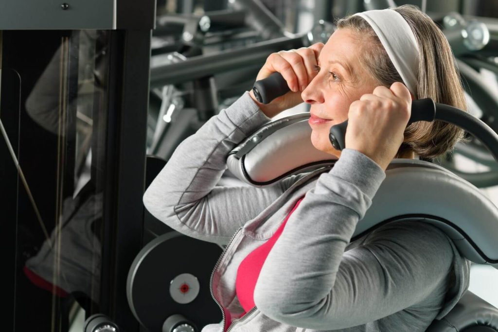 Oudere vrouw op een ab crunch machine in de sportschool