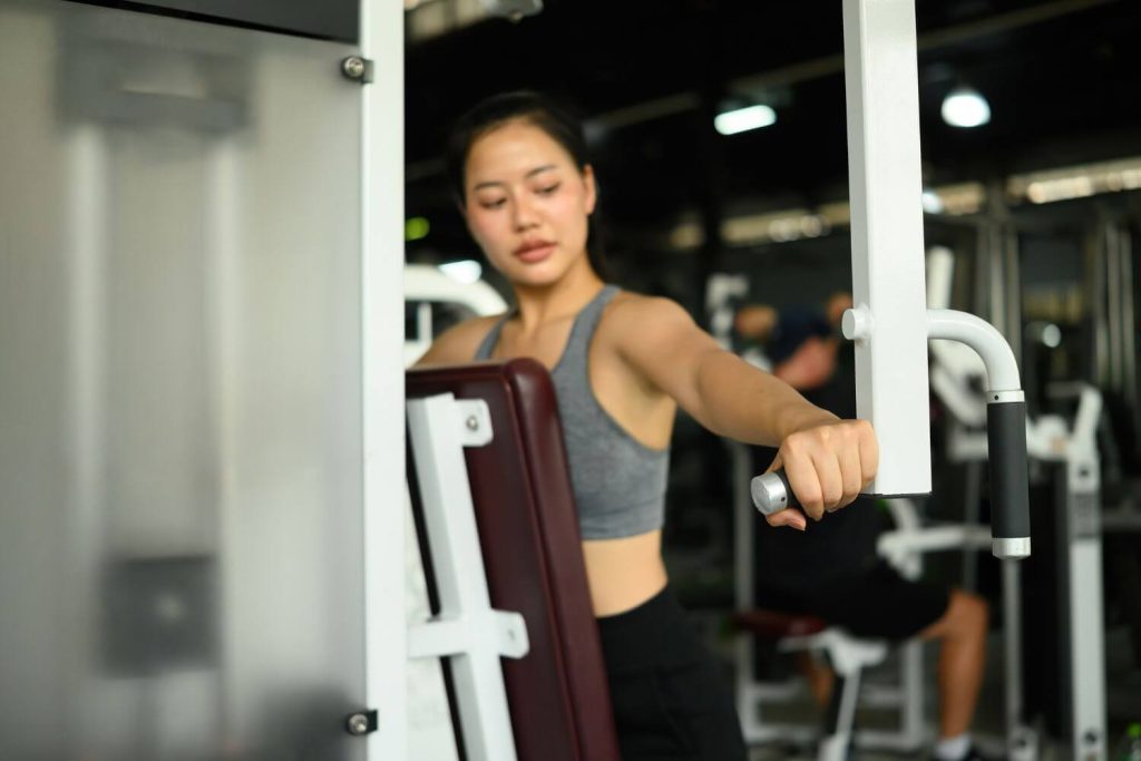 jonge vrouw op een rear deltoid machine in de sportschool