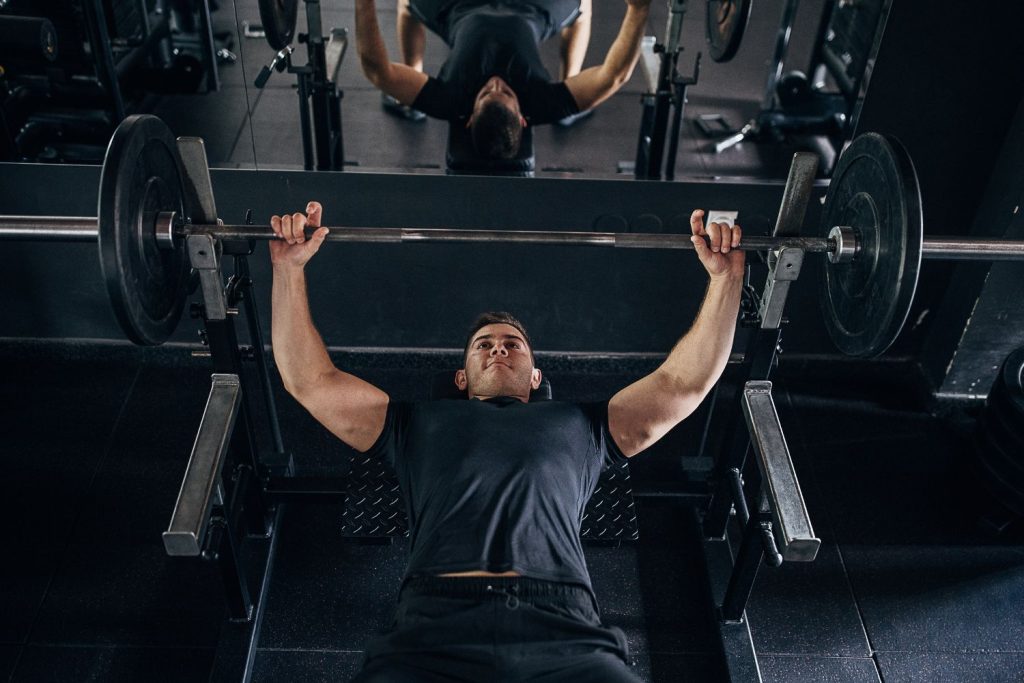 Man voert een pin press uit op een powerlifting rek in de sportschool