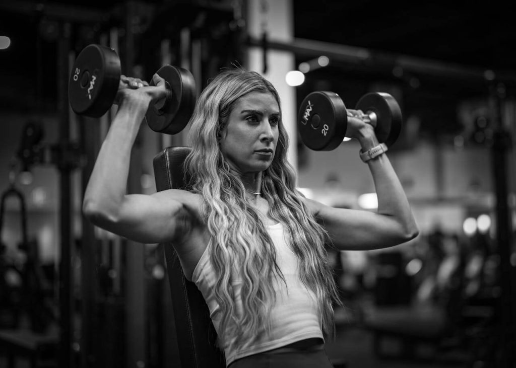 Gespierde vrouw traint in de sportschool met dumbbells
